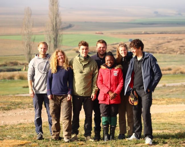 Foto 1 Group picture of young people standing on a field with trees in the background